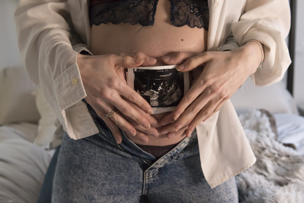 Imagen de una sesión de fotografía de embarazada con un enfoque en el vientre, capturando la conexión especial entre la madre y su bebé.